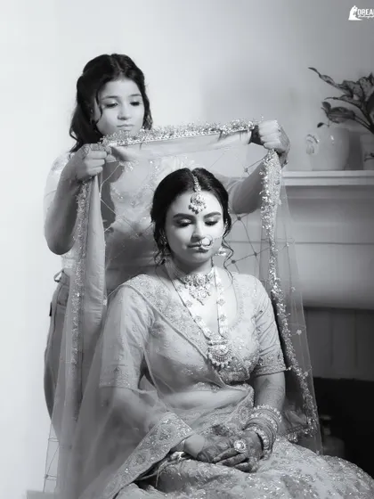 A touching black and white moment of a bridesmaid helping bride Anvita with her veil, capturing the quiet support system behind every bride.