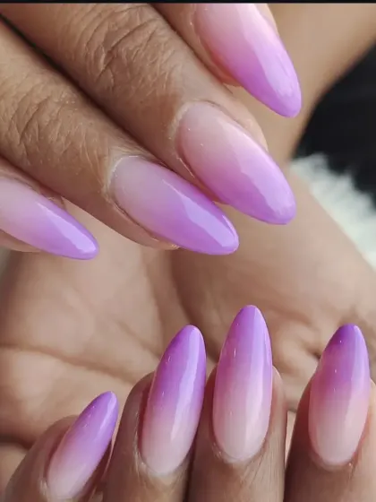We create seamless color blends with our ombre nail services. This set shows a beautiful fade from a natural base to a vibrant lilac on long, almond-shaped extensions.