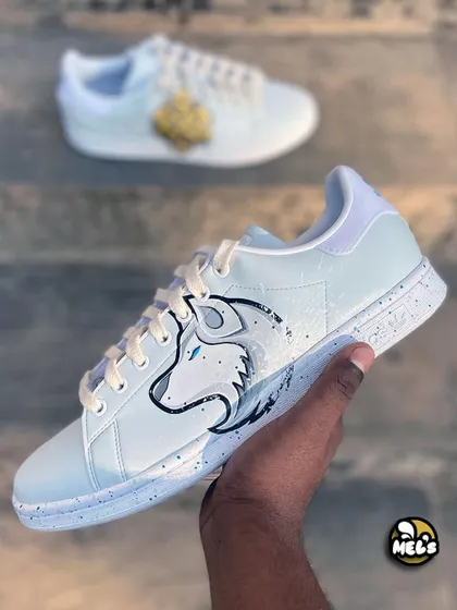 A hand-held shot of the white wolf custom sneaker, with the Karma shoe blurred in the background.