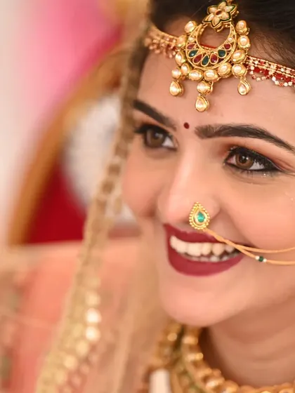 A close-up of the bride's happy smile. A bold, matte red lip is a classic choice for a Gujarati bride, and it looks stunning on her.