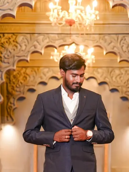 A handsome portrait of the groom-to-be in a stylish suit, taken in a grand, ornately decorated hall.