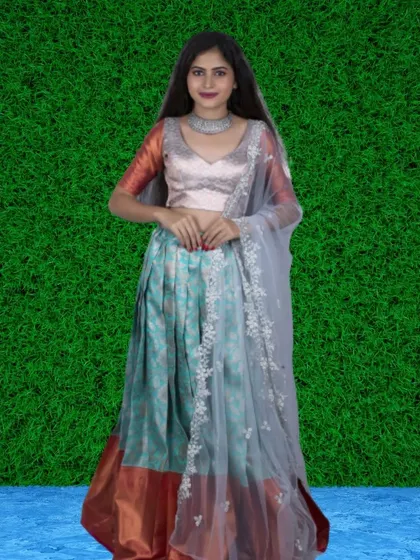 A beautiful combination of a silk-like skirt in shades of blue and copper, paired with a simple blouse and an embroidered sheer dupatta.
