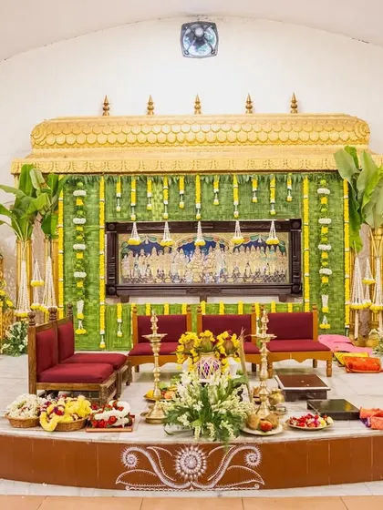 For this traditional indoor ceremony at the Art of Living center, we designed a classic stage with banana leaf pillars and yellow floral decor, honoring timeless customs.
