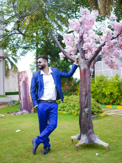 A stylish shot of the groom-to-be in a sharp blue suit, posing in a garden setting. I make sure both partners get their hero shots.