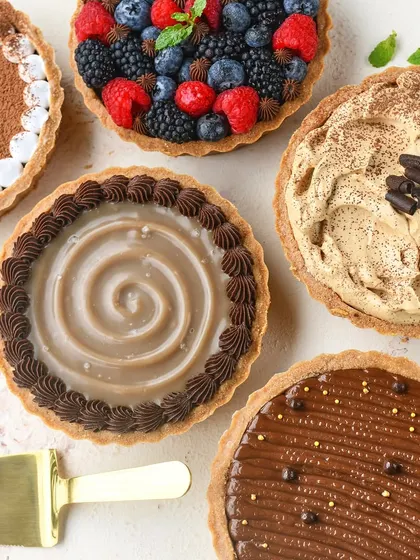 A beautiful flat lay of my signature chocolate tarts with various toppings. You can see the Fresh Berry, Salted Caramel, Coffee Mousse, and Nutella options, showcasing the variety I offer.