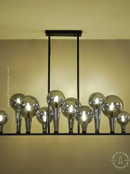 A playful yet chic linear chandelier featuring a series of chrome-finished glass bubbles. The highly reflective surface and modern design make it a striking addition to a kitchen island or a contemporary dining space.
