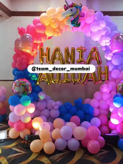 A close-up of the unicorn birthday setup, highlighting the foil name balloons and the dense, colorful balloon arrangement.