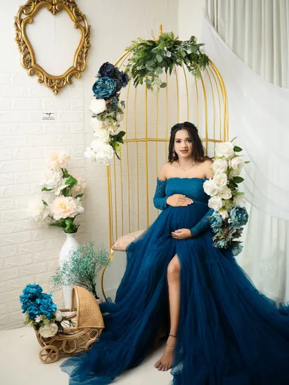 A full-length portrait showing the beautiful flow of the teal gown. The mother-to-be looks confident and radiant in this glamorous studio setup.