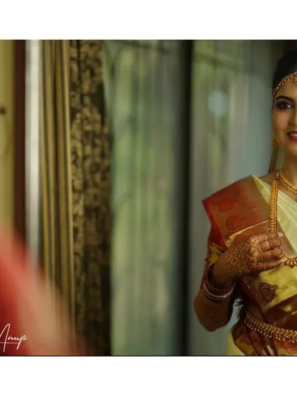 A reflection shot capturing the bride's final look. The makeup is subtle and elegant, focusing on flawless skin and defined eyes.