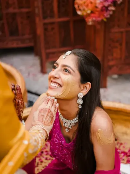 A beautiful, gentle moment of the bride getting haldi applied. Her serene expression and the soft lighting create a peaceful and lovely portrait amidst the fun.