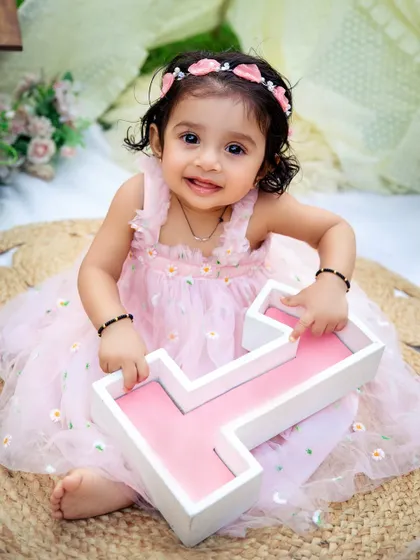 Holding her number one. This is a classic and adorable pose for a first birthday, celebrating this huge milestone in a sweet and simple way.