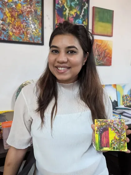 A participant proudly holding her miniature canvas painting of a rustic door. Even on a small scale, the details are beautiful.