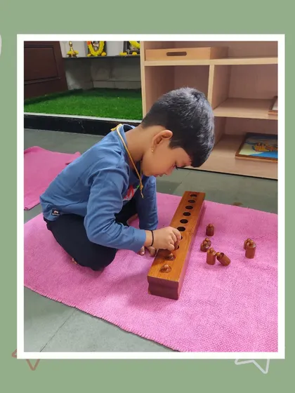 Ishan works with the knobbed cylinders, an activity that refines his ability to discriminate by size. His focused effort is a testament to the engaging nature of Montessori materials.