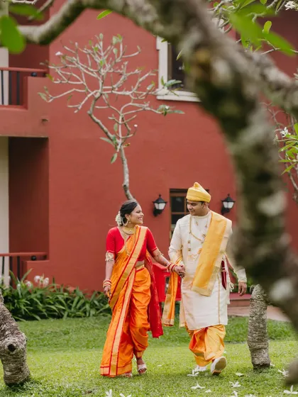 A romantic shot of a Maharashtrian couple walking through a garden, framed by tree branches, creating a natural and intimate feel.