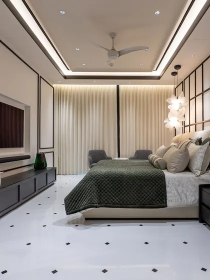 A bedroom designed with a bold black-and-white concept. The geometric paneling behind the bed adds architectural interest, while the dark wood furniture provides a grounding contrast to the white floors and walls. The space feels both dramatic and sophisticated.