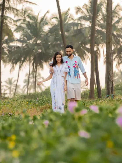 A pre-wedding shot of the couple taking a romantic walk through a field of flowers in Goa.
