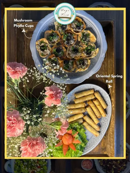 A beautiful platter featuring our Mushroom Phyllo Cups and Oriental Spring Rolls, adorned with fresh flowers. A perfect appetizer combination.