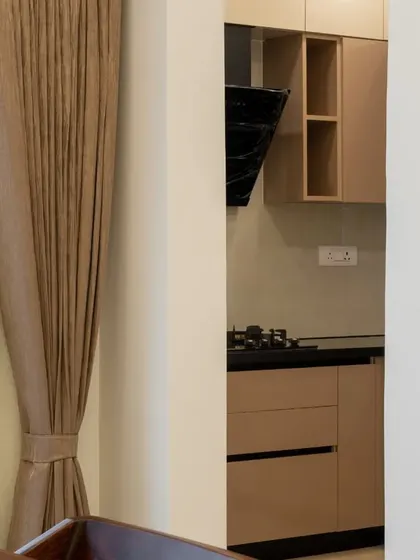 A glimpse into the modular kitchen from the dining area, showcasing the clean lines and neutral color palette of the cabinetry.