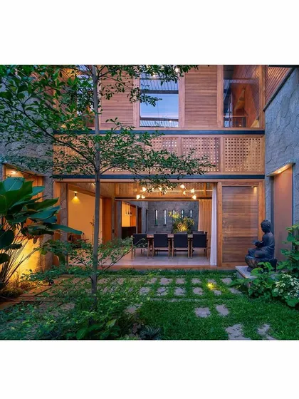 A view from the courtyard looking back into the home's dining area. The placement of a Buddha statue and carefully selected plants creates a peaceful, meditative atmosphere in this indoor-outdoor space.