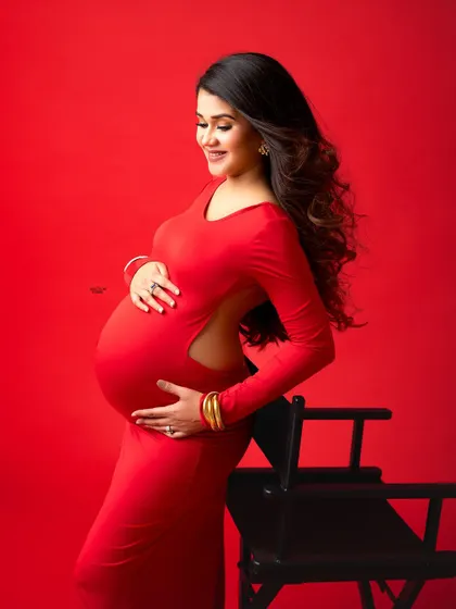 This side-profile shot highlights the beautiful cut of the open-back red gown and the gorgeous baby bump. It's a mix of elegance and allure.