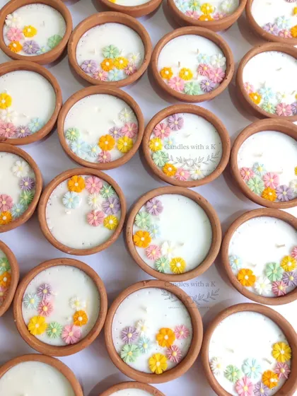 Clay pot candles decorated with tiny, colorful flowers, a delicate and intricate design for festive gifting.