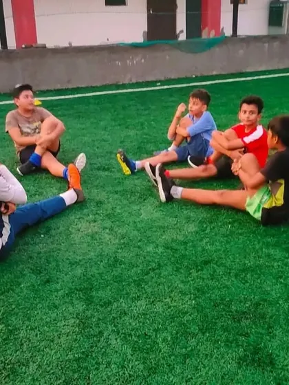 A coach sits with young players during a cool down stretch. These moments are great for building rapport and discussing the session, ensuring players understand the lessons of the day.