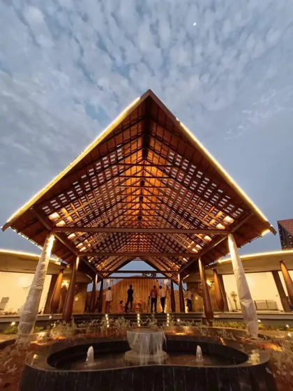 The entrance to our upcoming resort in Madurai features a dramatic, high-pitched roof with an intricate wooden lattice. This grand porte-cochère sets a welcoming and impressive tone for arriving guests.