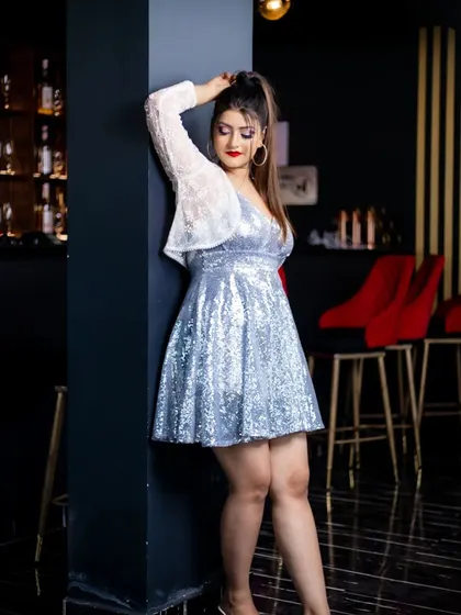 This party look is styled with a delicate white shrug over a silver sequin dress. The makeup remains glamorous with a high ponytail and striking red lip, showing how to layer for a chic evening style.