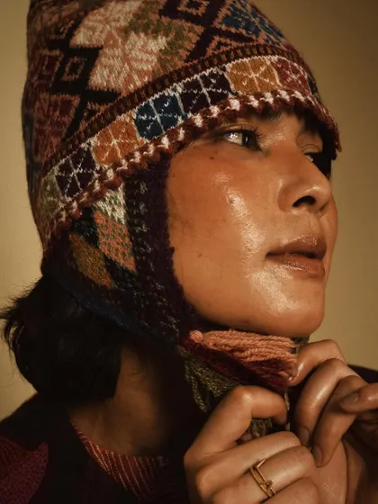 A close-up portrait highlighting a beautifully crafted winter hat from House of Wandering Silk. The focus is on the intricate details and the model's soft expression.