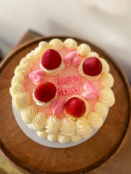 A sweet and simple vintage-style cake. This pink buttercream cake is decorated with classic piping, topped with fresh strawberries for a fresh and pretty look.