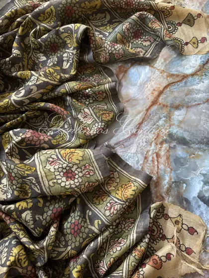 The Kalamkari silk dupatta is artfully draped to showcase its fluidity and the complexity of its hand-painted floral design. The off-white and green border adds a classic touch.