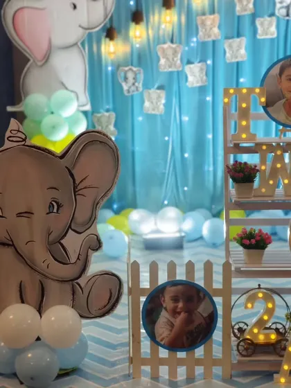 A close-up of a cute baby elephant-themed party, showing custom character cutouts and personalized photo displays on a decorative shelf.