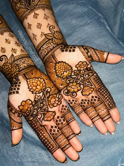 A gorgeous floral design that extends up the arm. The use of negative space with scattered motifs on the forearm contrasts beautifully with the denser patterns on the palm.