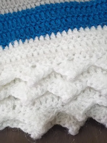 A detailed look at the white crest pivot edging I added to this semi-circle shawl. This decorative border gives the piece a polished and wavy finish.