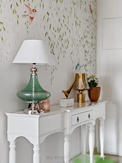 A close-up of the foyer console, styled with a beautiful green glass lamp and brass accents.