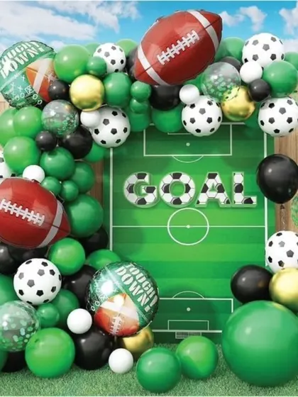 A dynamic sports-themed party decor with a football field backdrop, and a mix of soccer and American football balloons.