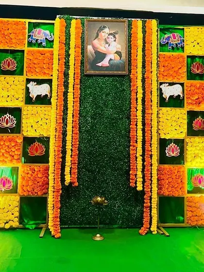 This backdrop is made of vibrant marigold panels in yellow and orange. It includes traditional motifs and a central portrait, perfect for creating a warm and inviting atmosphere for a Seemantham.