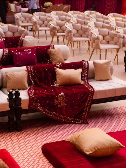 A mix of traditional diwans with rich velvet throws and modern upholstered chairs offers guests varied and comfortable seating options during a long ceremony.