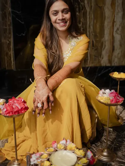 A happy bride surrounded by flowers, with her beautiful dark mehendi stain on full display.