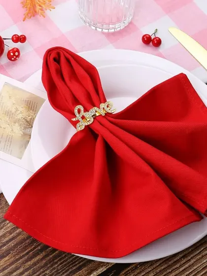 Set the mood for love with this elegant Valentine's Day detail. A simple red napkin is transformed with a gold 'Love' napkin ring, creating a romantic and unforgettable touch for your special dinner.