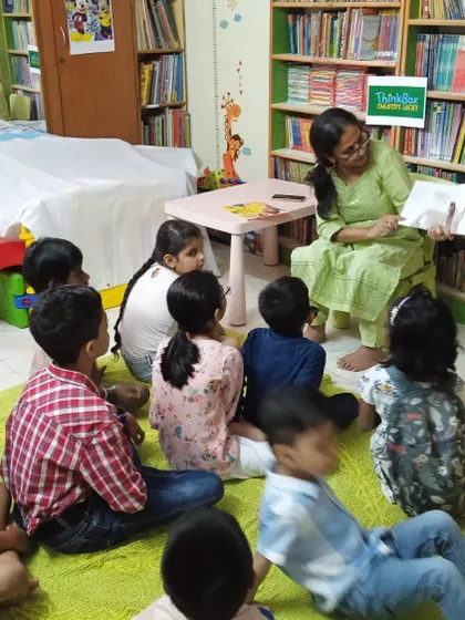 A storyteller reads aloud to a group of children, who are listening intently. Reading stories that break stereotypes helps shape open and inclusive minds from a young age.