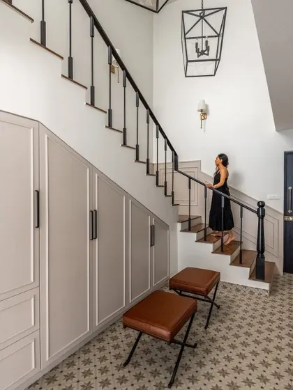 A view of the foyer staircase, featuring classic wainscoting and a traditional lantern-style pendant. We designed this space to be a beautiful and functional entry point into the home.