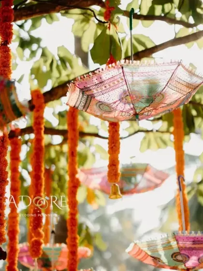 A colorful detail from a 'Kashiyatre' ceremony. These decorative umbrellas and hanging marigold strings add a festive and traditional touch to the outdoor setting.