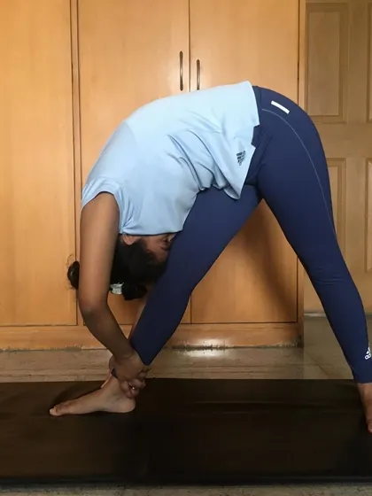 The same student deepens their hamstring stretch by holding the ankle. This shows the progression that is possible with consistent practice, even at home.