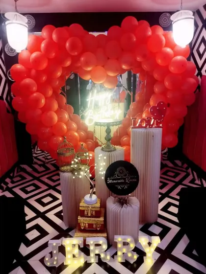 A bold red heart-shaped balloon arch against a striking black and white patterned background.
