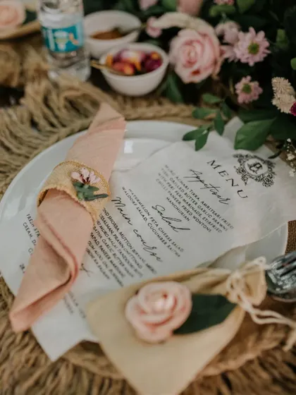 Every detail on the table is crafted to create a feeling of timeless romance. From the custom-printed menu to the delicate floral napkin rings, this setup invites guests to a truly special dining experience.