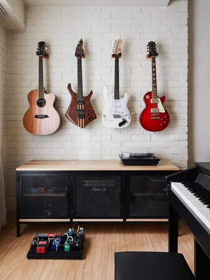 We created a dedicated guitar wall for the client's collection in the Zen House jam room. The instruments become functional art, displayed against a white painted brick wall for a touch of industrial texture.