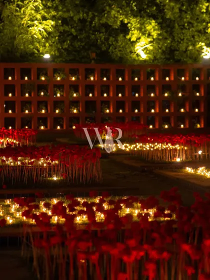 A close-up of the outdoor light installation. I used fields of artificial red poppies, uplit from below, and grids of flickering candles to create a surreal and magical garden of light.