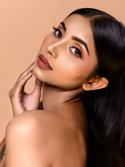 A classic beauty portrait with a focus on natural-looking makeup. The soft lighting and clean background ensure the model's features are the main subject.