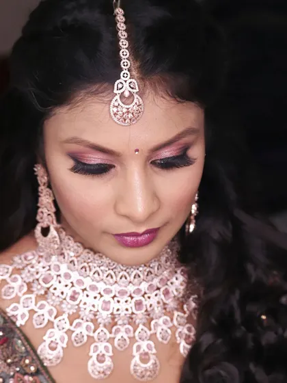 A close-up of a glamorous reception look. The focus is on the dramatic pink and purple smokey eye, paired with a full set of lashes and a beautiful diamond choker.